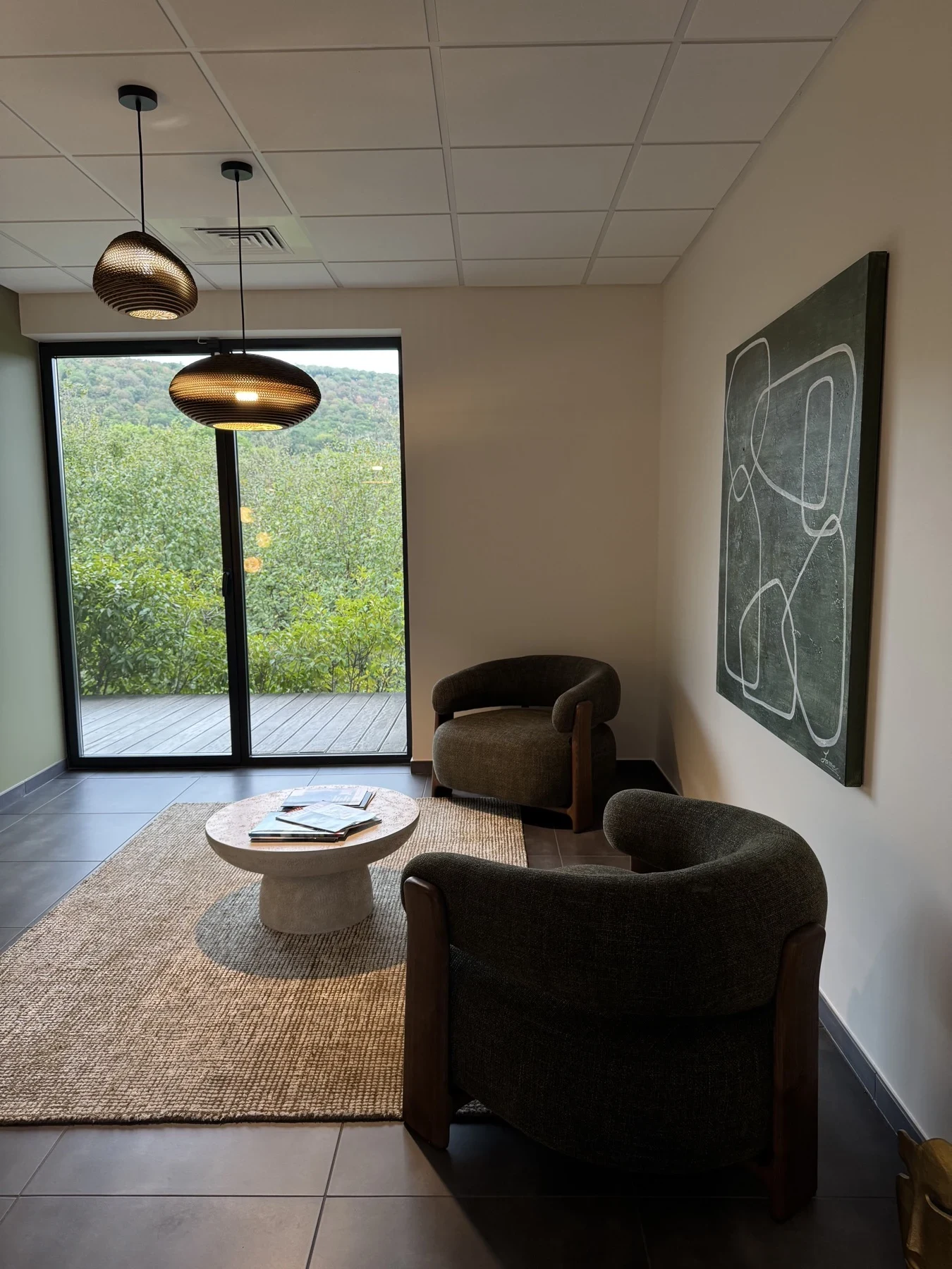 Salon d’attente avec fauteuils, table basse et vue sur la verdure